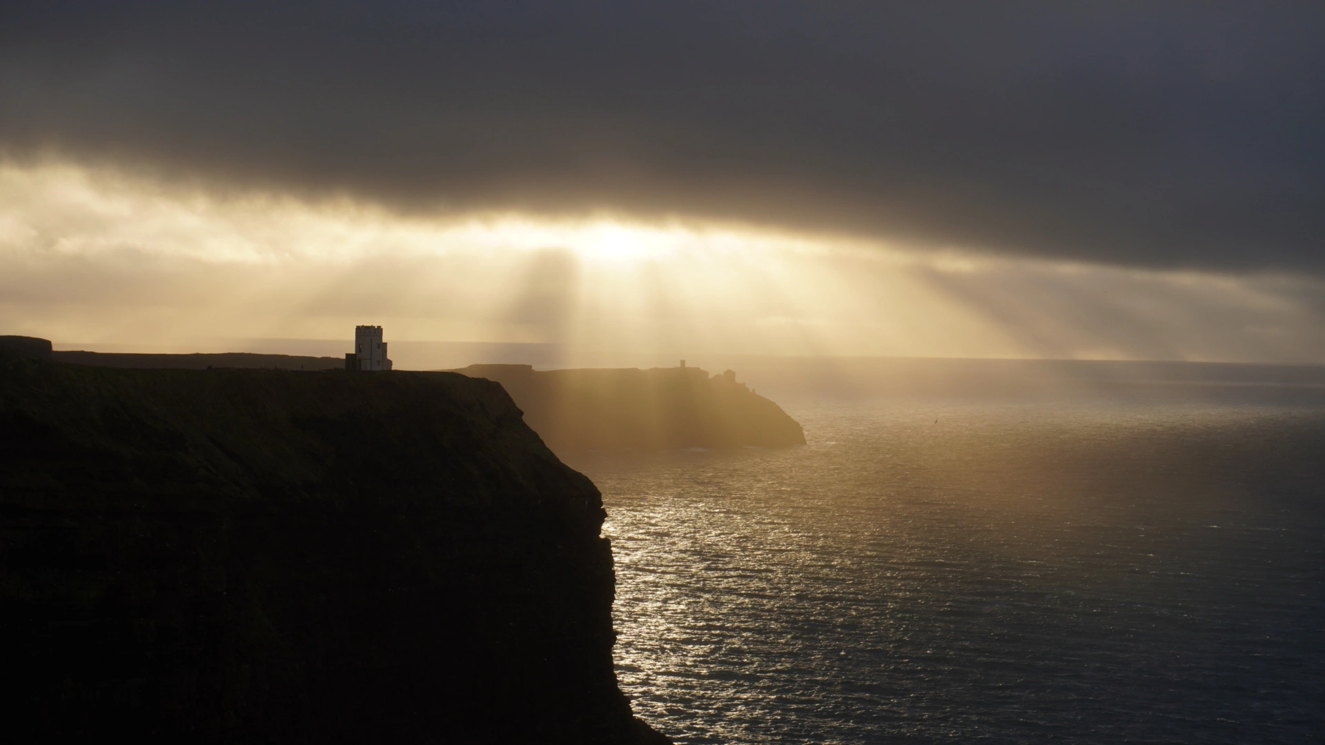 Photograph of the Cliffs of Moher in Ireland. The sky opened up for us for just a second to reveal these incredible sun rays.